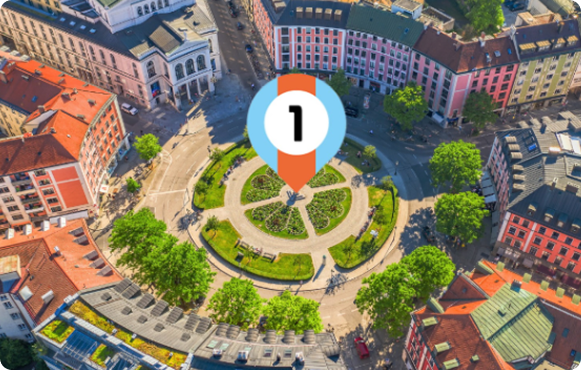 Luftaufnahme eines Münchner Platzes mit dem Firstplace Immobilien Logo in der Mitte – Symbol für lokale Immobilienkompetenz und Präsenz in München.